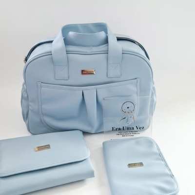 Conjunto de mala azul claro, bolsa e estojo com placa dourada em fundo branco
