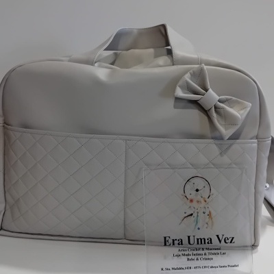 Mala cinza clara matelassê com laço decorativo e cartão promocional ao lado