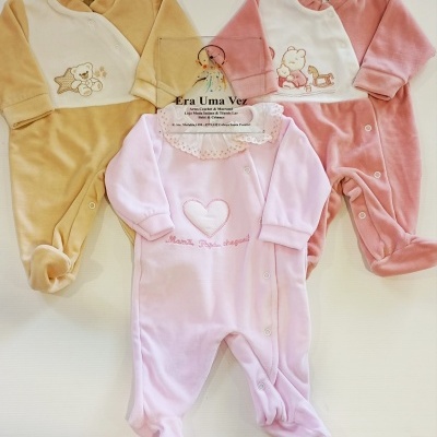 Três pijamas de bebé de veludo em tons bege, rosa e branco, com padrões de ursinhos e corações