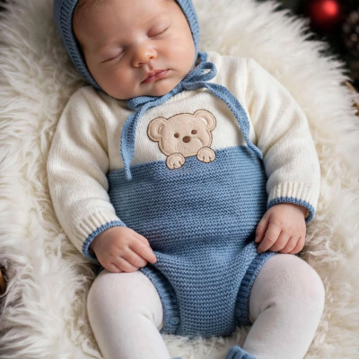 Bebé adormecido em roupa de malha azul e branca com ursinho bordado