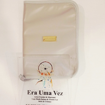 Pasta bege claro com placa dourada e etiqueta transparente com apanhador de sonhos e texto promocional