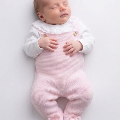Bebé vestido com macacão de malha rosa com laços e camisa branca com gola rendada