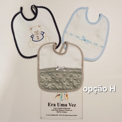 Três babetes para bebé com diferentes cores e texturas, incluindo desenho de urso e detalhes em laços