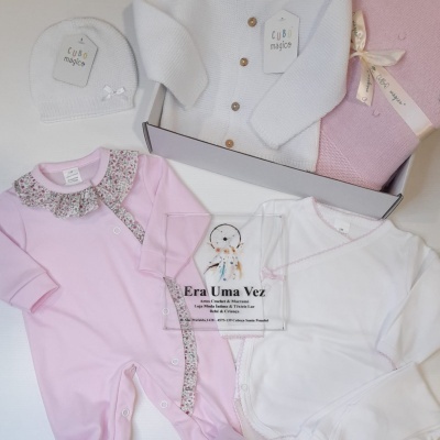 Conjunto de roupa de bebé em rosa e branco com camisola de malha e gorro.