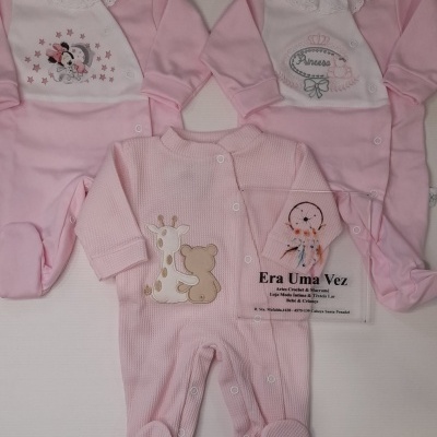 Três macacões de bebé rosa com diferentes padrões e texturas