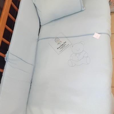 Berço de madeira com protector e almofada azul claro bordada com ursinho