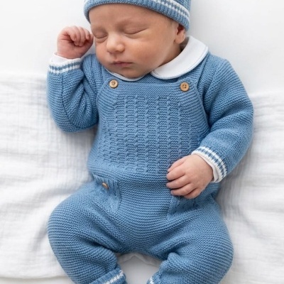 Bebé com fato e gorro de malha azul deitado