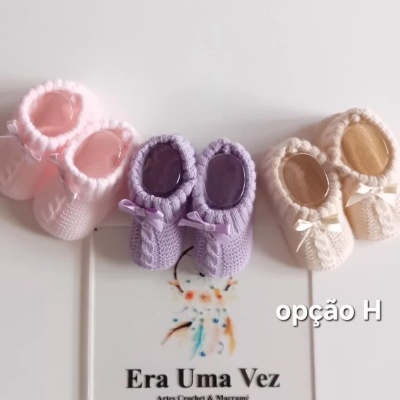 Três pares de sapatinhos de bebé de croché coloridos com laços