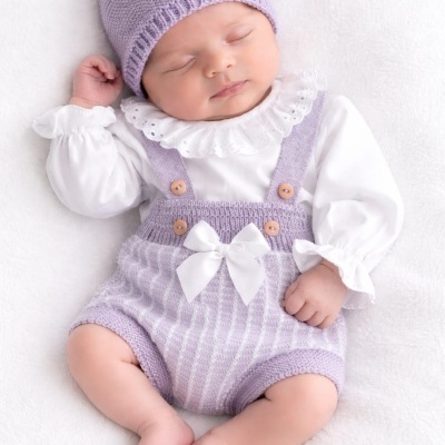 Bebé a dormir com roupa de malha lavanda e blusa branca com fundo branco