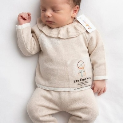 Bebé a dormir com roupa de malha bege clara e etiqueta com texto Era Uma Vez