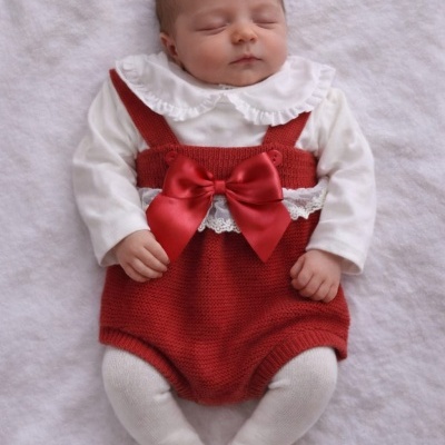 Bebé com roupa branca e vermelha a dormir sobre tecido branco