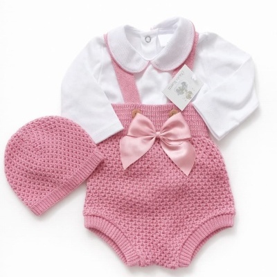 Conjunto de roupa de bebé branco e rosa com body, macacão e gorro em malha texturizada.
