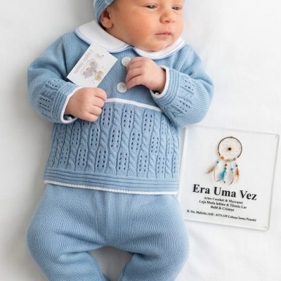 Bebé deitado com conjunto azul de malha e gorro