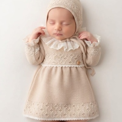 Bebé a dormir com vestido e boné bege de malha e gola branca bordada