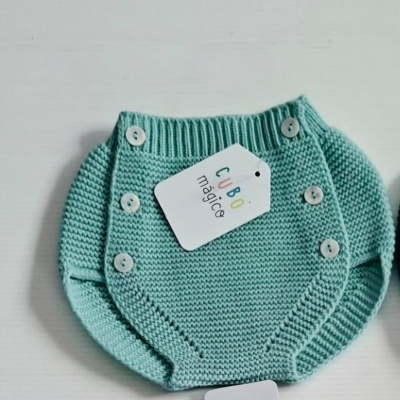 Culote verde de malha para bebé com botões e etiqueta branca com texto colorido.