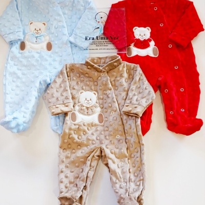 Três macacões de bebé azul, vermelho e bege com desenho de urso e textura de bolinhas.