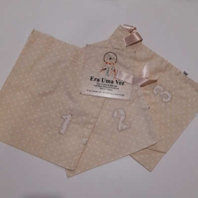 Três sacos de tecido bege com estrelas brancas e números 1, 2, 3 bordados e etiqueta plástica