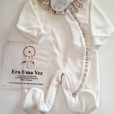 Macacão branco para bebé com padrão floral no colarinho e botão, etiqueta Criações Cristina e cartão com filtro dos sonhos.