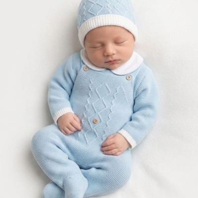 Bebé com roupa de malha azul claro com gorro branco