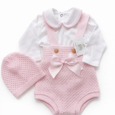 Conjunto para bebé com body branco e calcinha de malha rosa claro com alças e laço, e gorro rosa claro