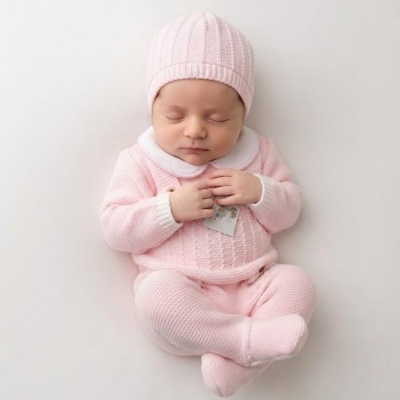 Bebé deitado com roupa de malha rosa clara e gorro