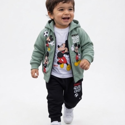 Criança a vestir casaco verde, t-shirt branca e calças pretas com estampados do Mickey Mouse.