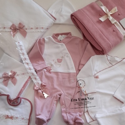 Conjunto de roupa de bebé rosa e branca com laços e manta rosa