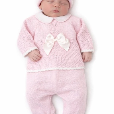 Bebé a dormir vestido com roupa rosa de malha com laço branco