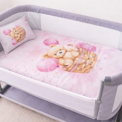 Berço portátil com roupa de cama rosa e estampa de urso com balões