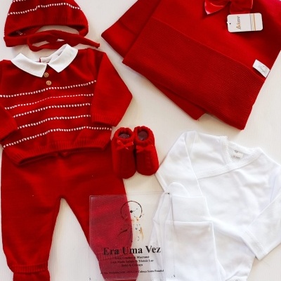 Conjunto de roupa de bebé vermelho e branco sobre uma superfície branca
