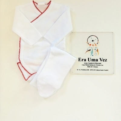 Conjunto de roupa de bebé branca com bordado vermelho e placa com texto Era Uma Vez.
