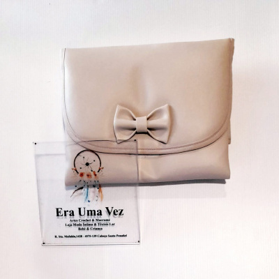 Bolsa bege clara com laço e flyer publicitário em fundo branco