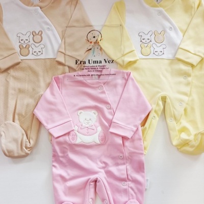 Três macacões de bebé em bege, amarelo e rosa com bordados de coelhos e urso