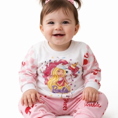 Bebé sorridente sentado com pijama Barbie colorido em fundo branco