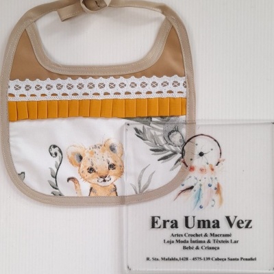 Babete bege claro com renda branca e estampa de leãozinho, cartão com texto Era Uma Vez e informações da loja.