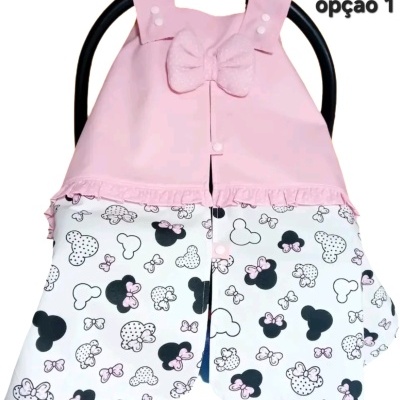 Capa de bebé rosa e branca com padrão de rato e laço, em assento de carro preto