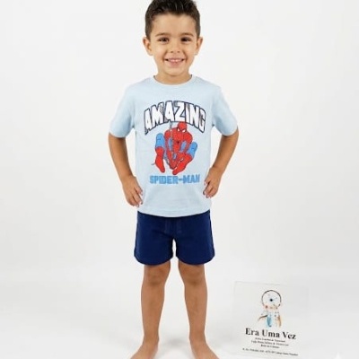 Rapazinho de t-shirt azul clara com estampa do Homem-Aranha e calções azuis escuros em fundo branco