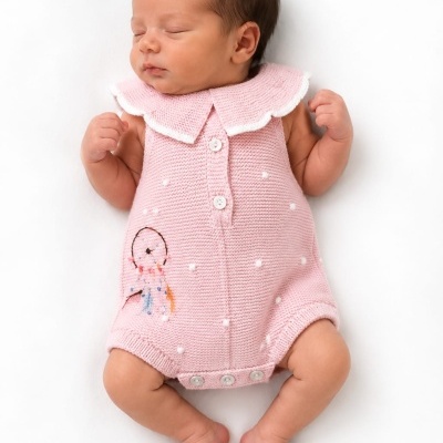 Bebé a dormir vestido com macacão cor-de-rosa de malha com gola branca e botões.