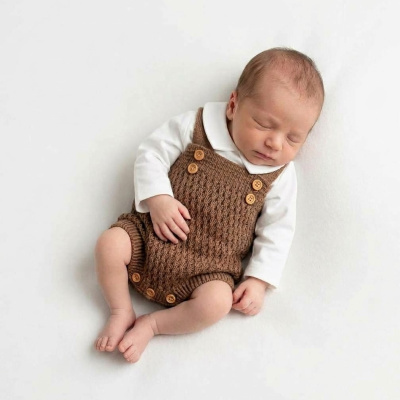 Bebé dormindo vestido com body branco e macacão castanho em malha