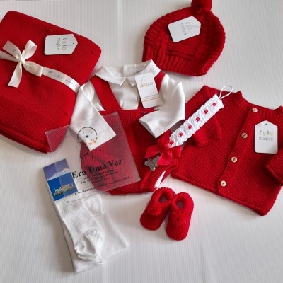 Conjunto de roupa de bebé vermelho e branco com acessórios e manta.