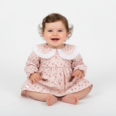 Bebé com vestido floral rosa e gola branca sentada