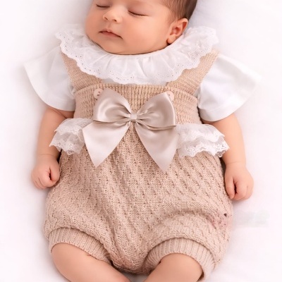 Bebé dormindo com roupa de malha bege e laço grande de cetim