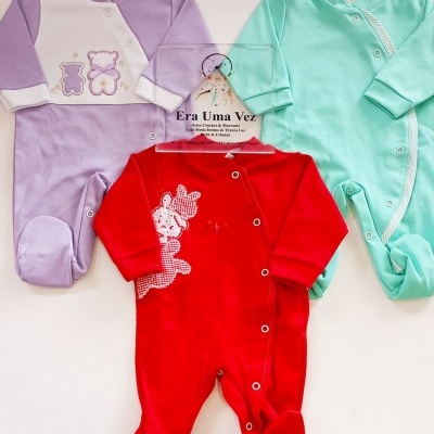 Três fatos de bebé coloridos com botões e aplicações, em lilás, vermelho e verde água