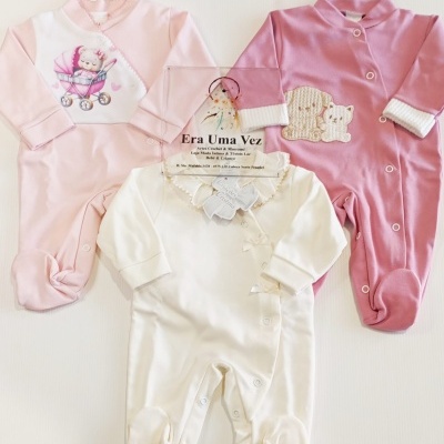 Três macacões de bebé em rosa claro, rosa escuro e branco com diferentes detalhes e botões-snap