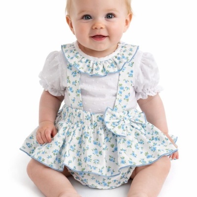 Bebé com vestido branco e saia e alças florais azuis