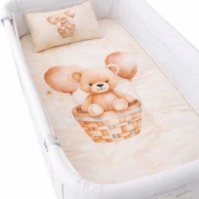 Berço branco com roupa de cama bege decorada com urso de peluche e balões