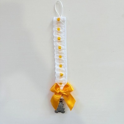 Prendedor de chupeta branco com detalhes amarelos e pendente metálico em forma de urso.