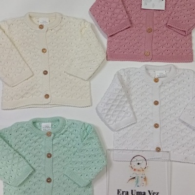 Casacos de bebé em malha com botões de madeira e uma placa com texto promocional