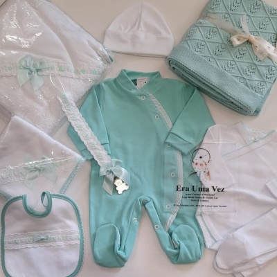 Conjunto de roupa e acessórios para bebé em branco e verde-água com detalhes rendados e manta de malha.