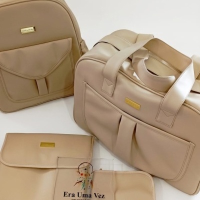 Produtos de couro sintético bege incluindo mochila, mala e estojos sobre fundo branco com sacola transparente etiquetada